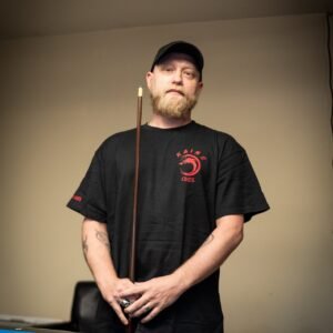 black kaine cues logo t-shirt worn by a team member against a neutral background.
